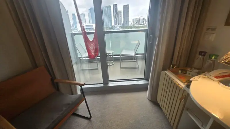 Cruise cabin with balcony and city skyline view on a Virgin Voyages ship
