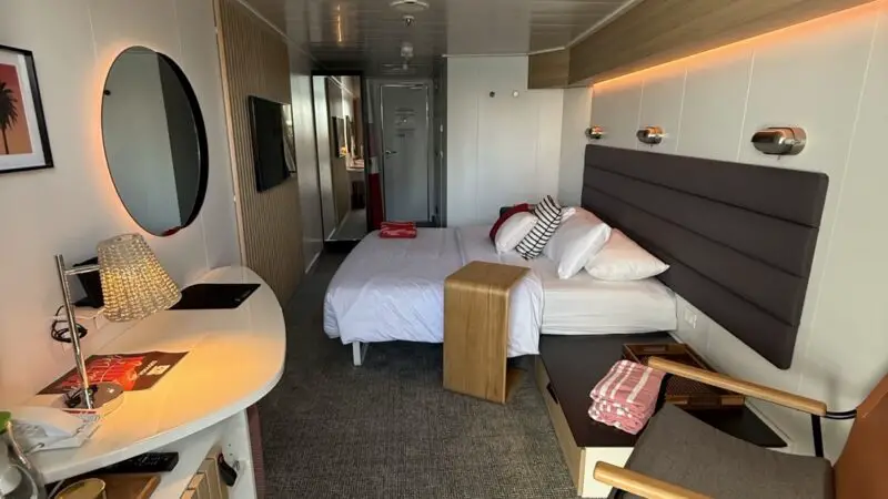 Virgin Voyages cruise ship cabin with bed, desk, and seating