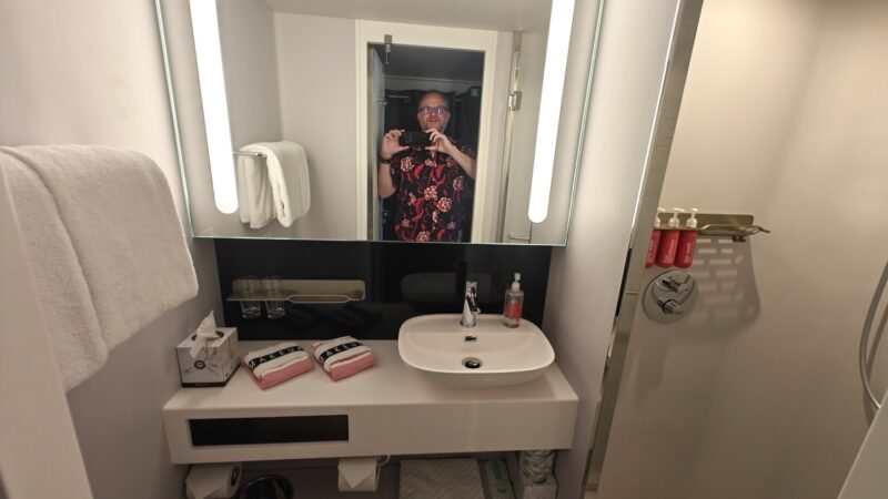 Self-portrait in a Virgin Voyages cruise ship cabin bathroom mirro