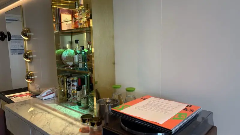 Bar area with a glass-front liquor cabinet, bottles, a globe, and a marble counter on a Virgin Voyages cruise ship