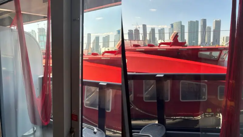 View from a Virgin Voyages cabin shows a red ship outside and the city skyline