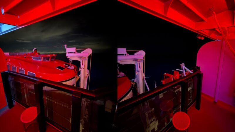 Red-lit Virgin Voyages cabin balcony overlooking the ship deck at night