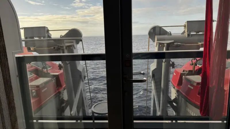 Balcony view from a Virgin Voyages cabin overlooking lifeboats at sea