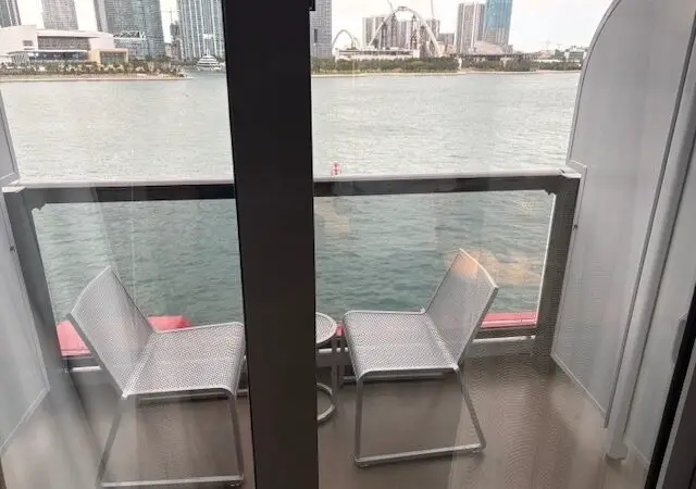 Balcony seating with two chairs on a Virgin Voyages cruise ship cabin overlooking water