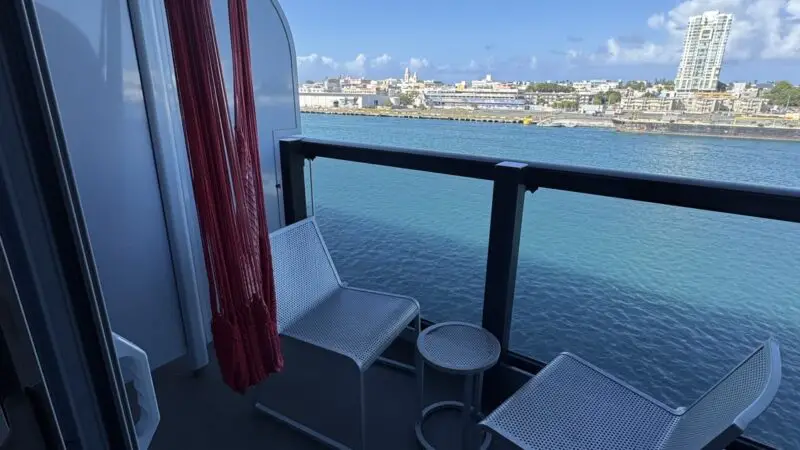 Balcony seating on a Virgin Voyages cruise ship with two white chairs and a small table