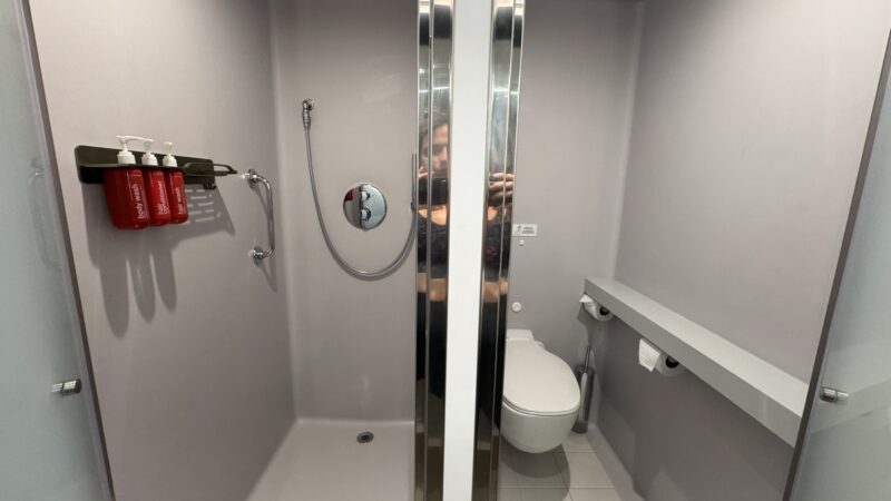 Compact cabin bathroom with shower and toilet on a Virgin Voyages cruise ship