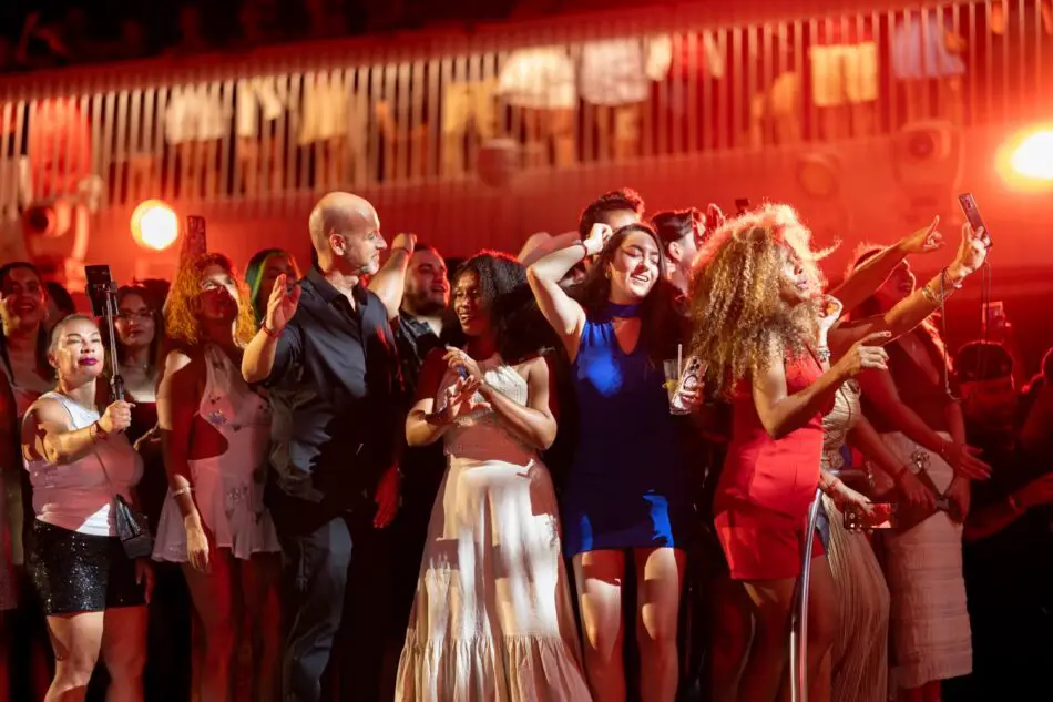 Diverse crowd dancing and taking selfies at a red-lit party