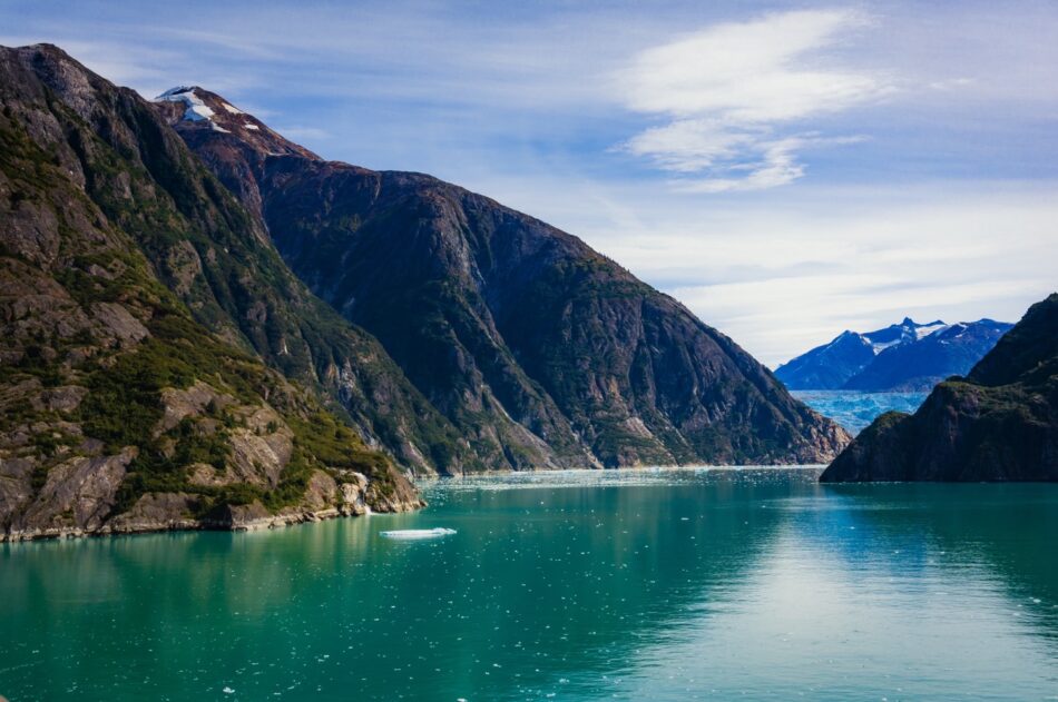 Steep rugged mountains loom over a turquoise glacial fjord