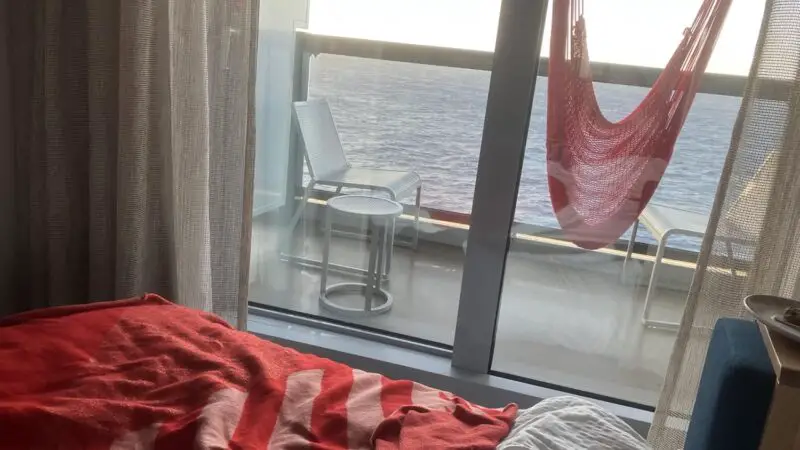 Virgin Voyages cruise ship cabin with balcony view of the sea and red striped bedding