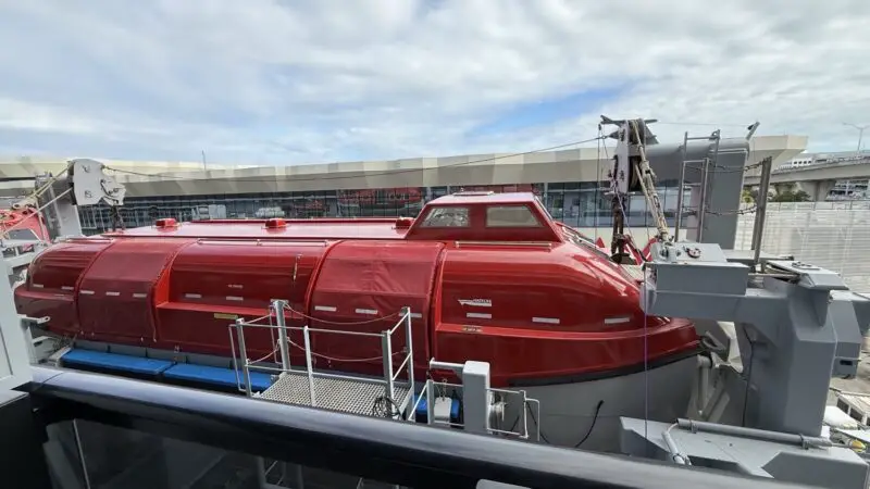 Red cylindrical equipment module on a ship deck with heavy machinery