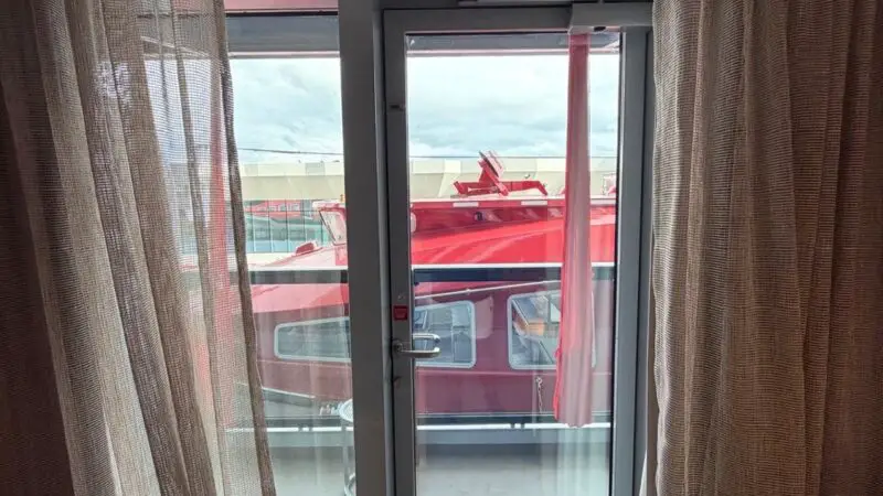 Virgin Voyages cruise ship cabin with balcony and red vessel outside