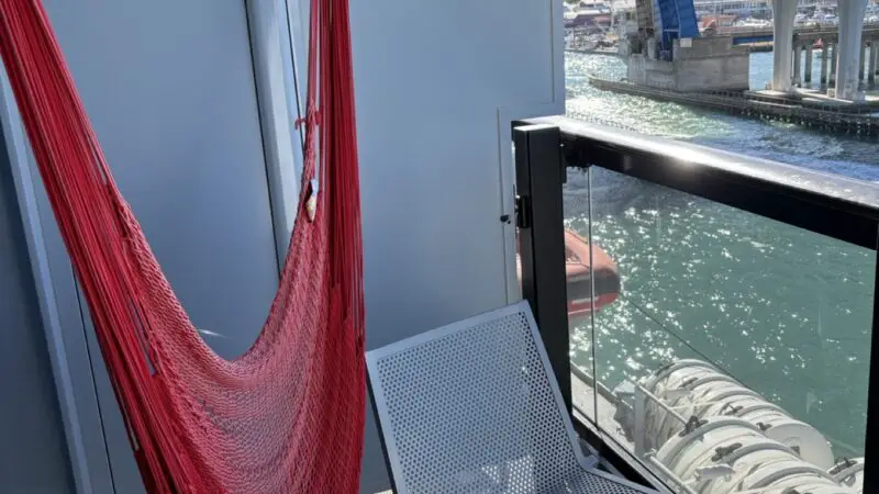 On a Virgin Voyages cruise ship balcony overlooking the water with a red hammock chair