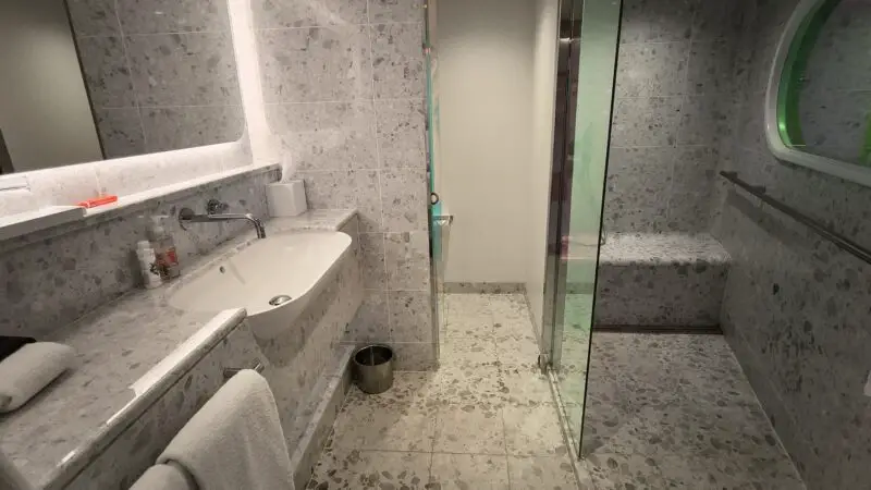 Grey terrazzo bathroom with sink and glass shower on a Virgin Voyages cruise ship cabin 12255Z