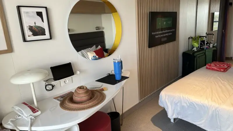 Virgin Voyages cruise ship cabin 10130Z with desk, round mirror, and neatly made bed