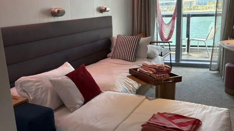 Virgin Voyages cruise ship cabin with two twin beds and balcony view