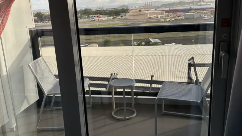 Balcony seating area in a Virgin Voyages cabin 10130Z with port view