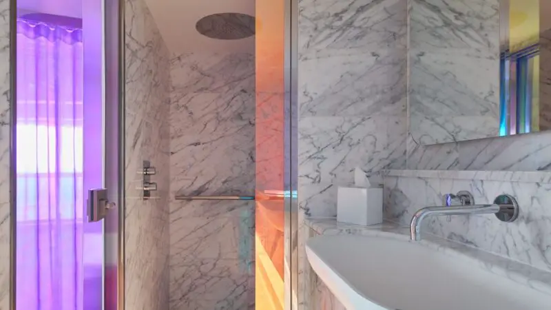 Luxurious marble bathroom with glass shower and sink on a Virgin Voyages cruise ship cabin