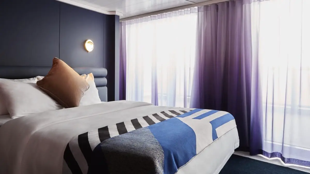 Virgin Voyages cruise ship cabin with a bed and purple curtains