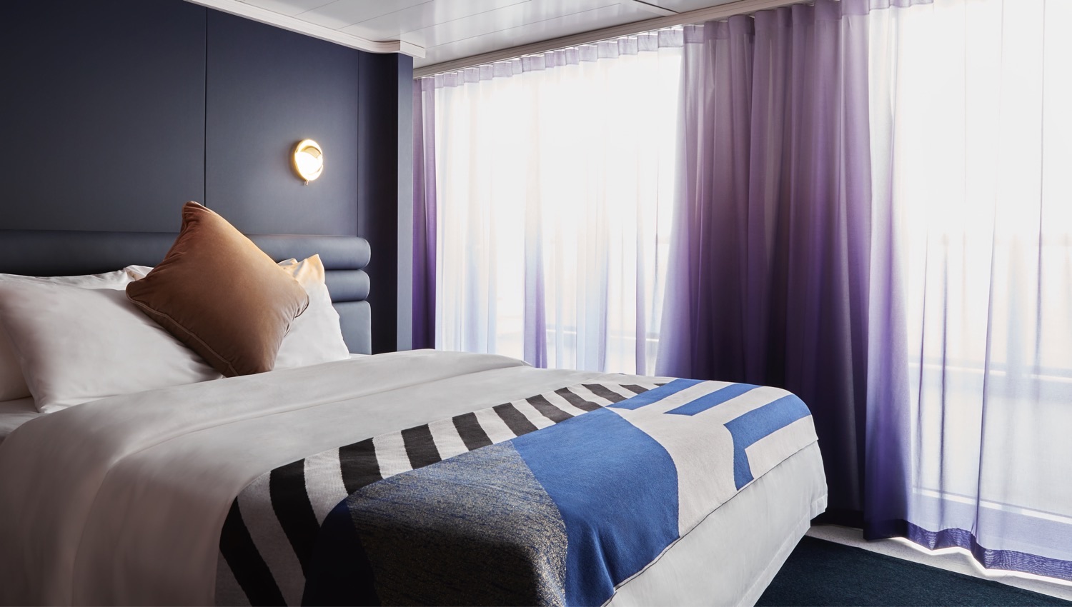 Virgin Voyages cruise ship cabin with a bed and purple curtains