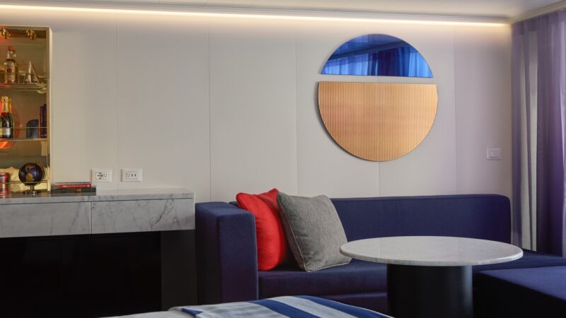 Virgin Voyages cruise ship cabin lounge with blue sofa and round marble table