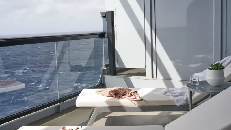 Balcony on a Virgin Voyages cruise ship with white lounge chairs and ocean view