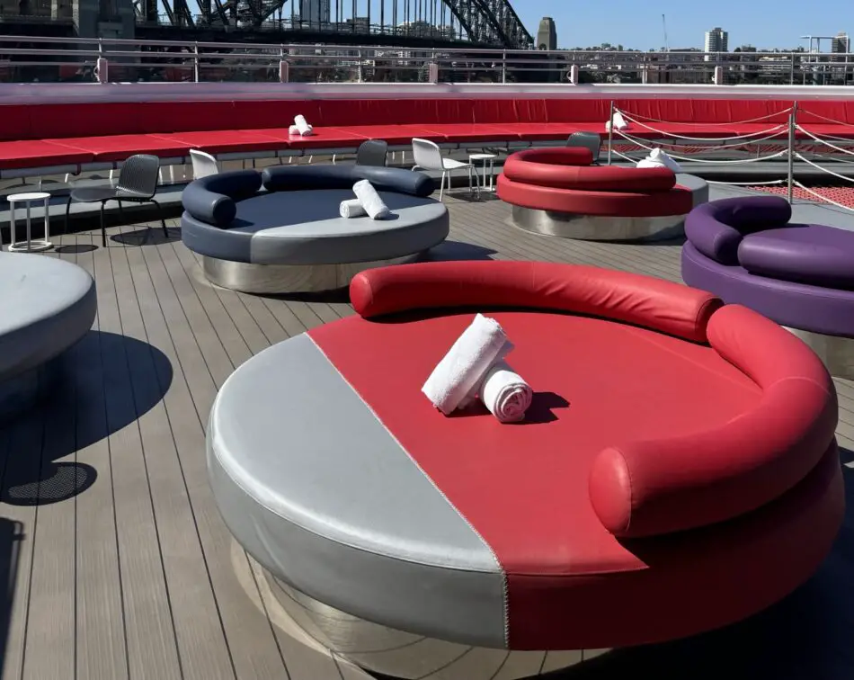 Bright circular red, blue, and purple lounge seating on a Virgin Voyages cruise ship deck