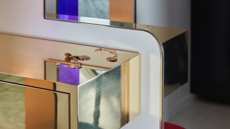 Gold mirrored vanity with jewelry on top in a Virgin Voyages cruise ship cabin