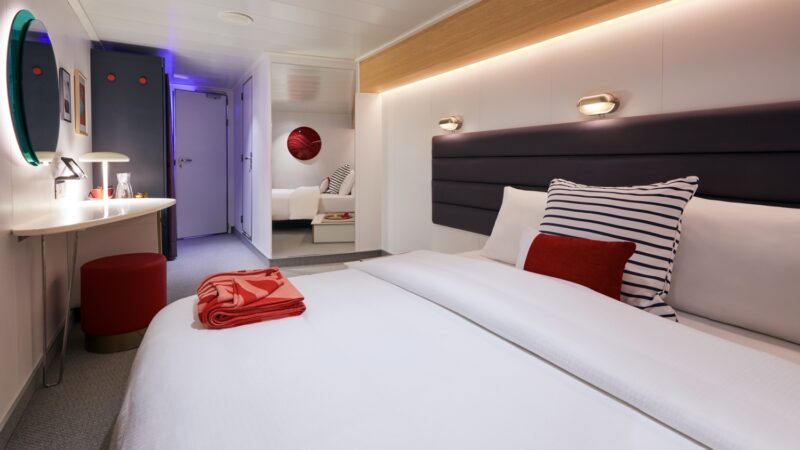 Virgin Voyages cruise ship cabin with a large bed and desk
