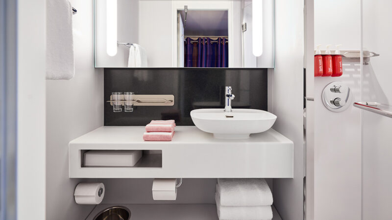 Virgin Voyages cabin bathroom with sink, mirror and towels