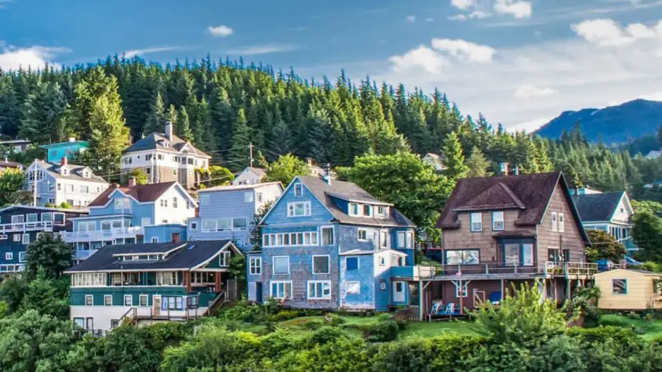 Colorful houses on a hillside with lush green trees in the background.