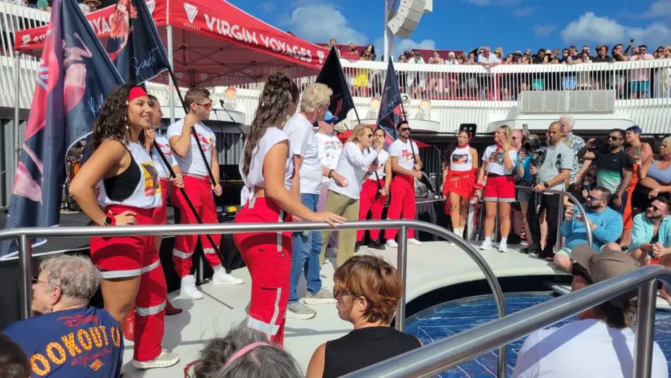 Performers in red uniforms on a Virgin Voyages cruise ship deck