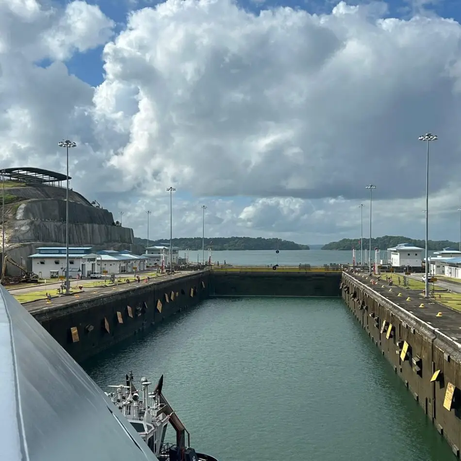 Cruise ship in a canal lock with concrete walls and open sea ahead