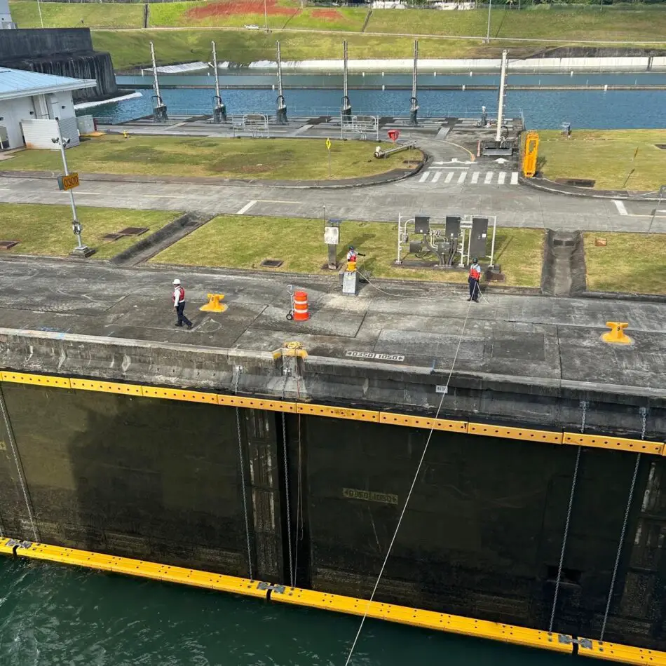 Industrial canal lock with workers in safety gear on the platform