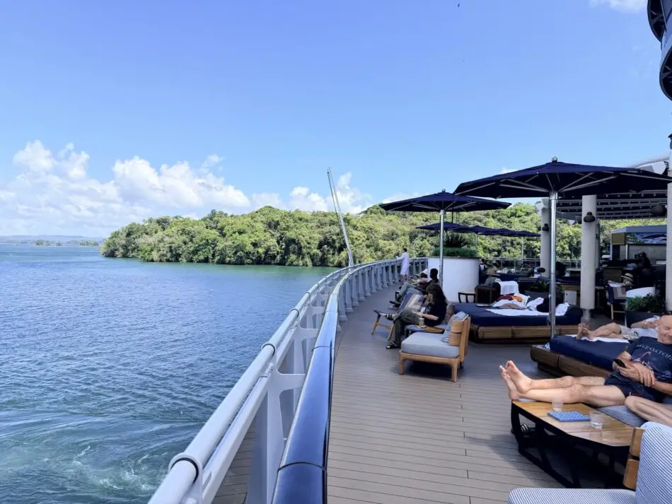 Outdoor deck on a Virgin Voyages cruise ship with sun loungers, umbrellas, and ocean views
