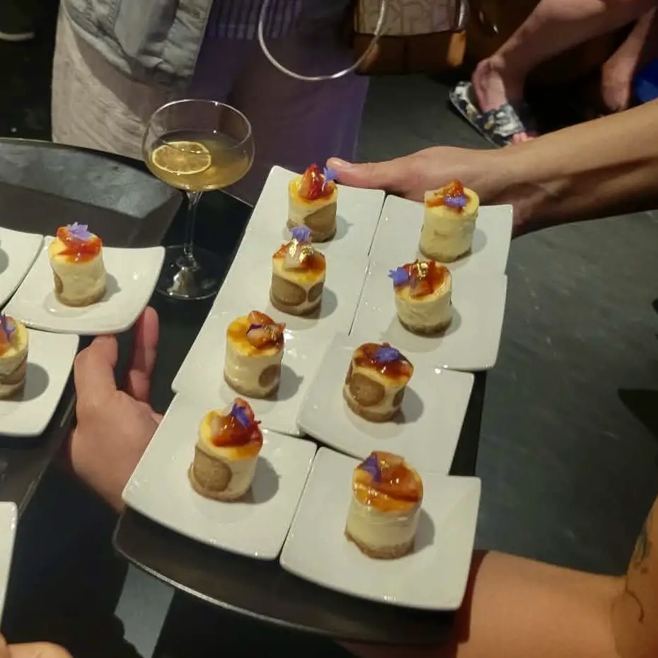 Tray of bite sized desserts with orange glaze and purple edible flowers