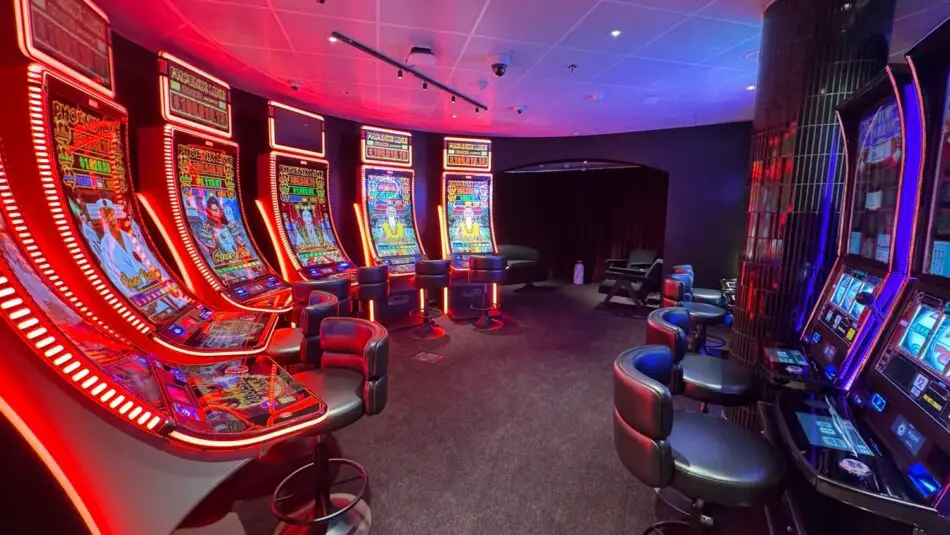 Casino on a Virgin Voyages cruise ship featuring neon-lit slot machines and seating