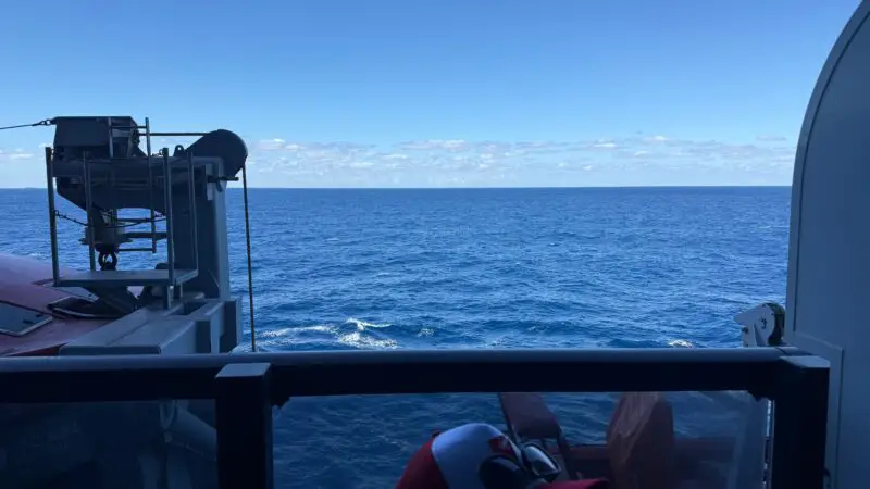 View from a Virgin Voyages balcony, showing the ocean and a lifeboat apparatus.