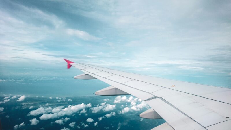 Airplane wing against a blue sky with clouds