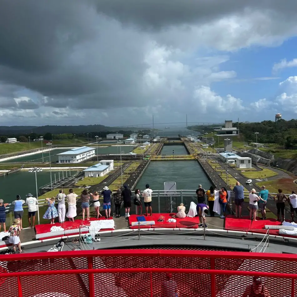 Passengers on a cruise ship deck overlook a canal lock