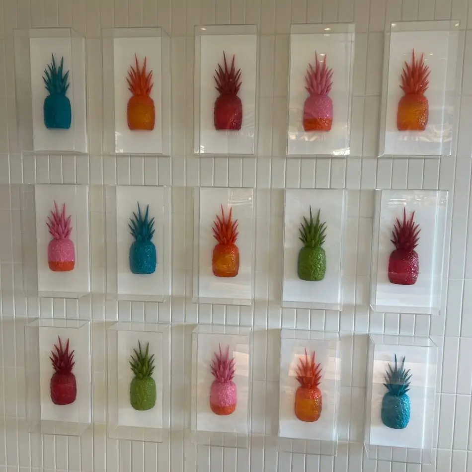 Colorful pineapple art prints mounted in frames on a tiled wall
