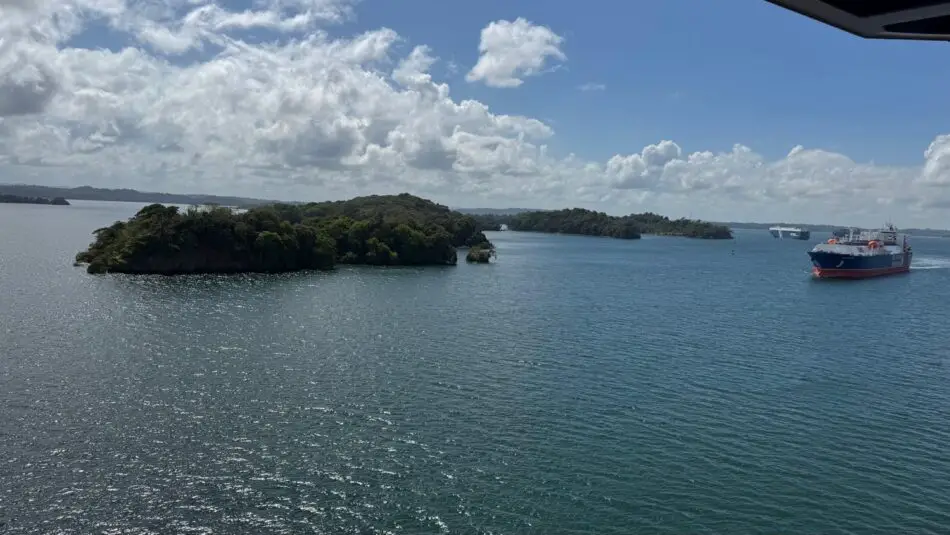 Ocean view from a Virgin Voyages cruise ship showing small islands and a cargo ship