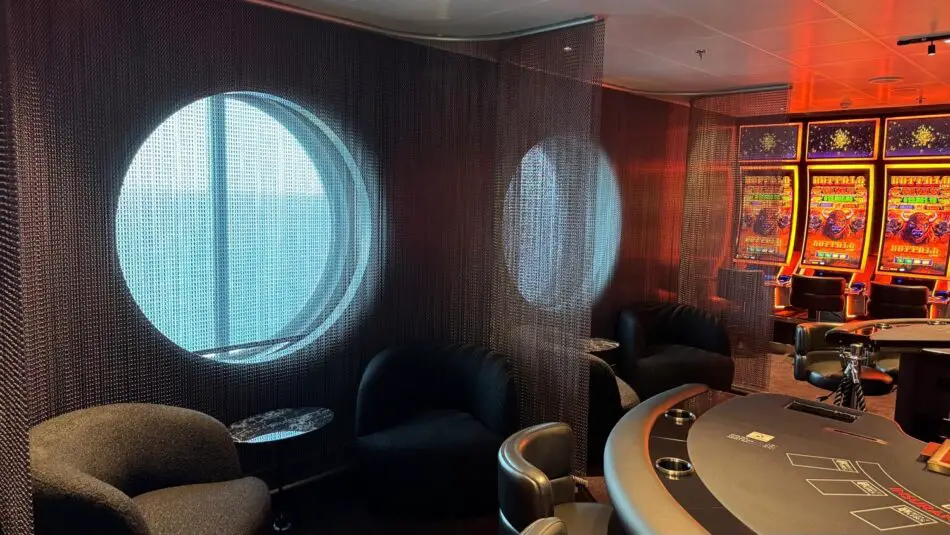 Virgin Voyages cruise ship casino lounge with round porthole windows and slot machines
