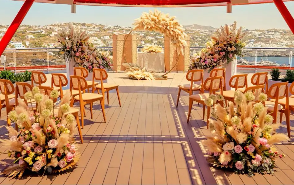 Virgin Voyages cruise ship deck wedding ceremony with floral arches and chairs