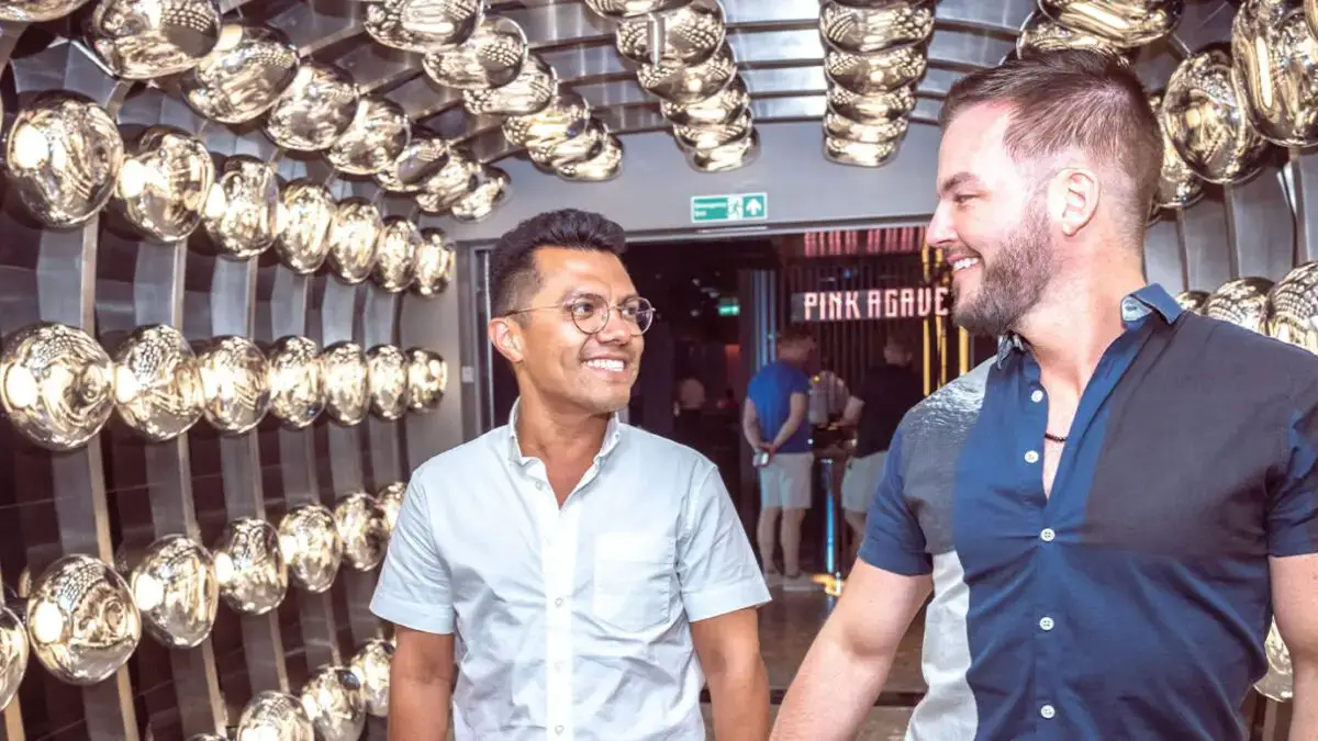 Two people smiling at each other while walking through a tunnel lined with reflective lights.