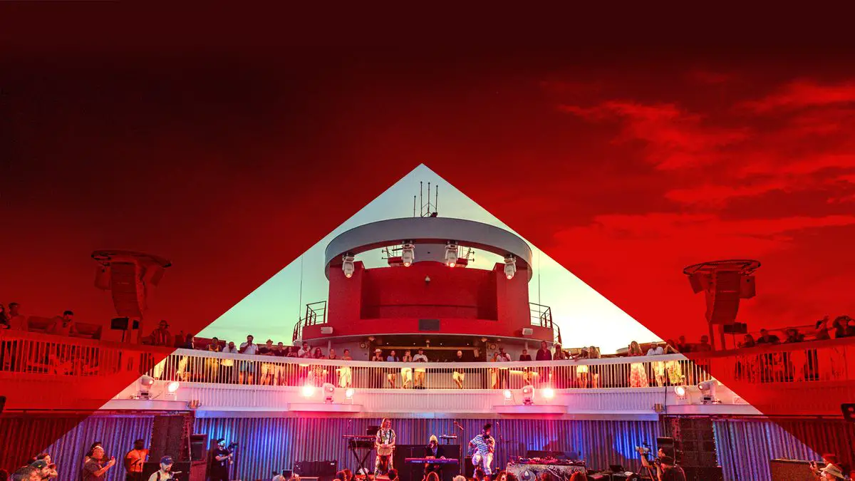 A cruise ship deck with people and a band, framed by a red triangular overlay against the sky.