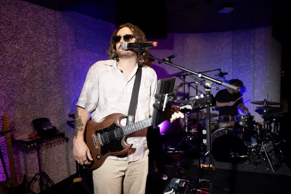 Guitarist in sunglasses performs with electric guitar on stage