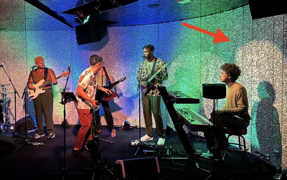 Five musicians perform on a colorfully lit stage