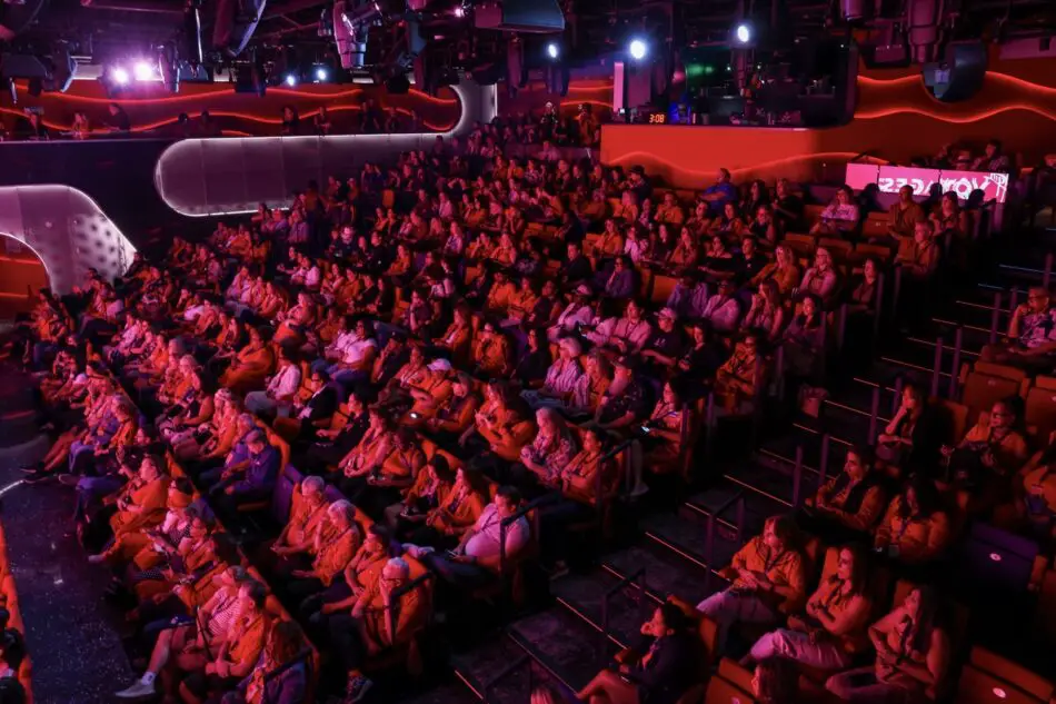 Large audience in a red-lit theater on a Virgin Voyages cruise ship