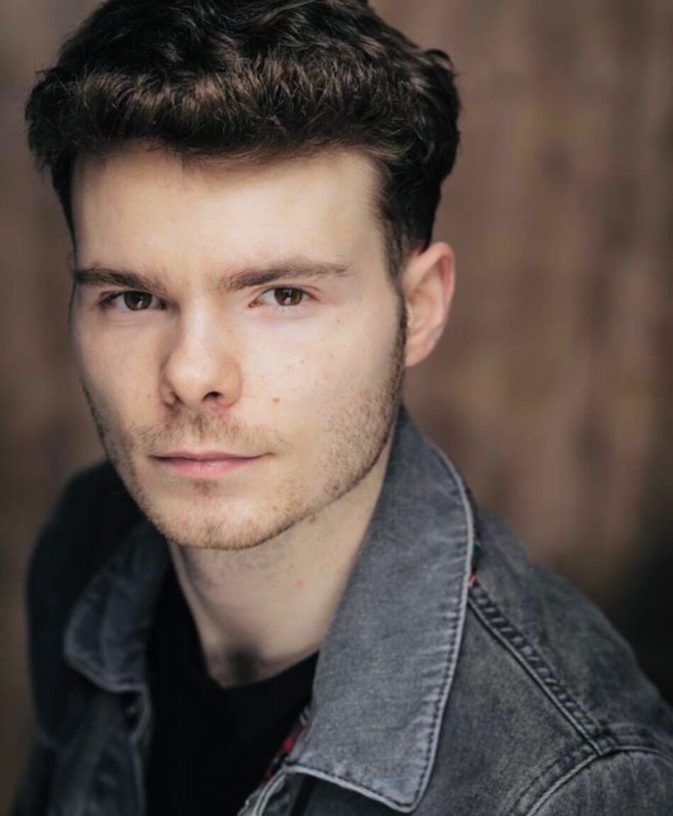 Close-up portrait of a man with dark hair wearing a denim jacket