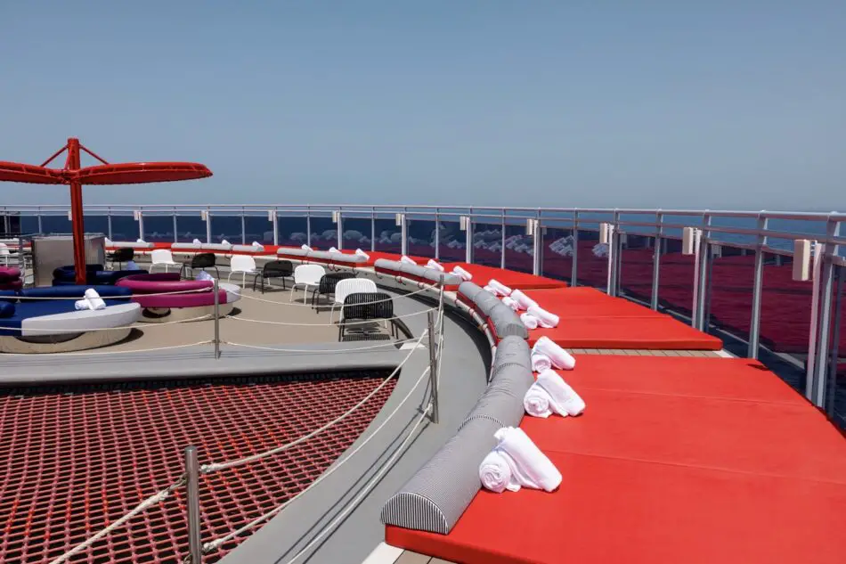 On a Virgin Voyages cruise ship deck with red loungers